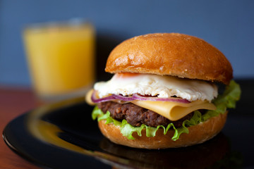 juicy burger with beef patty and fresh vegetables; consists of: buns, sweet sauce, onion rings, sweet pepper, lettuce, cheese, eggs