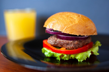 juicy burger with beef patty and fresh vegetables; consists of: buns, sweet sauce, onion rings, sweet pepper and green salad