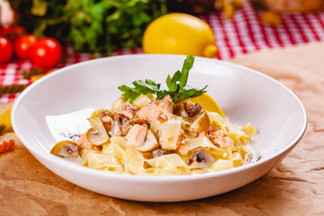 Pasta with salmon and mushrooms on white plate. Close up