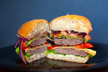 juicy burger with two pork cutlets and fresh vegetables; It consists of: buns, sweet sweet sauce, onion, pepper, tomatoes, green salad and cheese