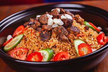 Traditional uzbek pilaf with meat, vegetables and garlic. Close up