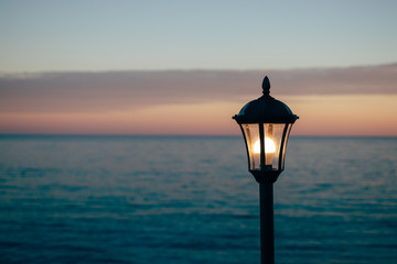 Old fashioned lantern glow near blue sea