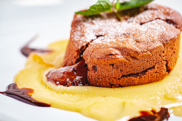 Chocolate fondant served with custard cream on white plate. Lava cake recipe. Close up