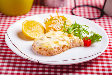 Salmon fillet served with risotto, arugula salad and lemon on white plate. Close up