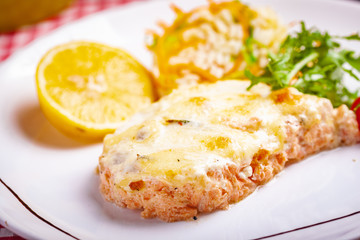 Salmon fillet served with risotto, arugula salad and lemon on white plate. Close up