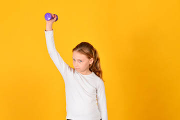 The girl is engaged in fitness with dumbbells, on a yellow background
