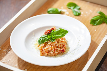 Risotto with sun-dried tomatoes and capers on white plate. Close up