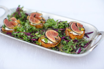 Plate with fig, pistacio and brie toastinis