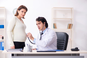 Old pregnant woman visiting young male doctor 