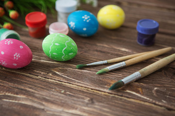 Colorful easter eggs, paint palette and brushes on wooden table. Top view with copy space