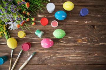 Easter concept. Colorful easter eggs, paint palette and brushes on wooden table. Top view