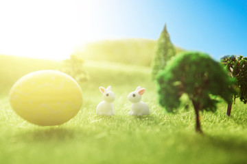 Yellow easter egg spring meadow with two white rabbit and easter eggs. Fairy tale