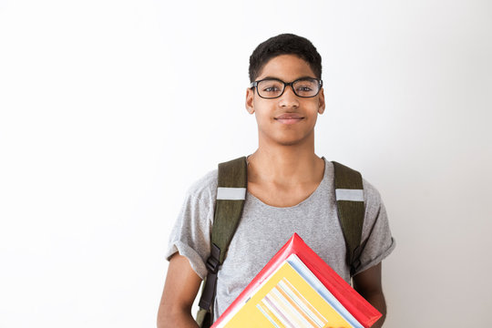 Happy afro american student in glasses with books. Portrait of a black young man with textbooks in his hands. Smiling boy with a backpack and notebooks on a white background. 