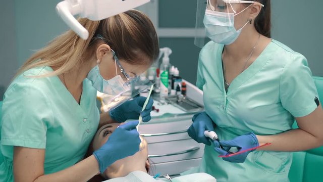 Female dentist with an assistant carry out teeth whitening procedure.