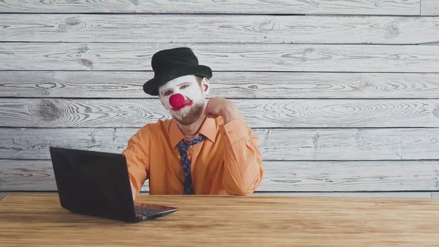 Office worker clown, clown concept at work. Businessman at the computer, work on a laptop.