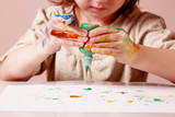 Art, creativity and happy childhood concept. Little cute child girl painting with colorful hands.