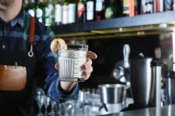 Barman holding White Russian cocktail in night club, closeup. Space for text