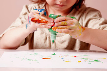 Art, creativity and happy childhood concept. Little cute child girl painting with colorful hands.