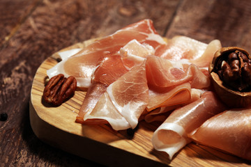 Italian prosciutto crudo or jamon with rosemary. Raw ham on rustic background