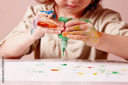Art, creativity and happy childhood concept. Little cute child girl painting with colorful hands.