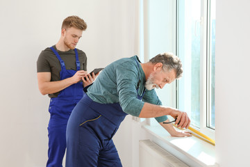 Obraz premium Service men measuring window for installation indoors