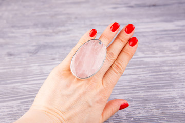 A silver ring on a hand with rose quartz
