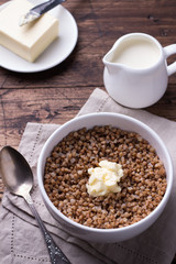 Buckwheat porridge with milk and butter on a wooden table