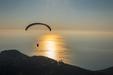 Beautiful shot of a paraglider flying into the sunset towards the ocean