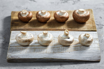 Composition with fresh champignon mushrooms on wooden board. Rustic style