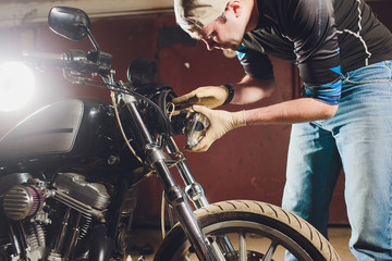 Fototapeta na wymiar Man fixing bike. Confident young man repairing motorcycle near his garage. replacement lamp in the headlamp