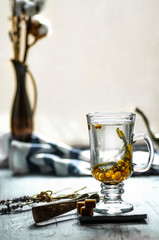 Buckthorn tea in a glass cup, vase with sweets and nuts. Tea time concept, healthy herbal tea