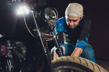 Fototapeta na wymiar Man fixing bike. Confident young man repairing motorcycle near his garage. caliper, brake pad replacement
