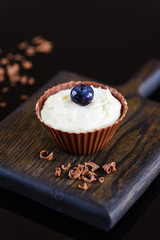 Chocolate tartlet with curd cream and blueberries on a wooden board