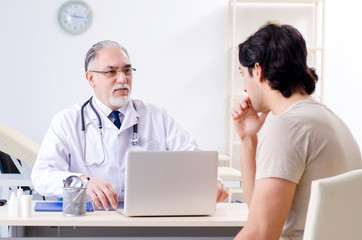 Young man visiting old male doctor 