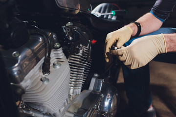 Fototapeta na wymiar Man fixing bike. Confident young man repairing motorcycle near his garage.