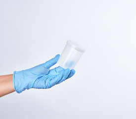 hand in a blue sterile glove holds a plastic container