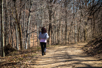 Woman walking in the forest with small poodle dog
