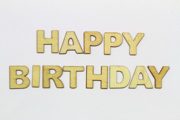 Happy birthday written with wooden letters on white surface