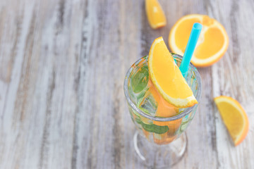 Citrus refreshing drink in a glass goblet on a wooden table. summer refreshing cocktail. Healthy food, drinks. orange and mint ice water. Copy space. horizontal view.