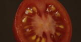 Rotate of the halves of fresh ripe cut tomato on a dark background