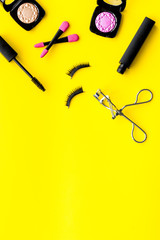 make up set with woman decorative cosmetic with eye shadows and mascara on yellow background top view space for text