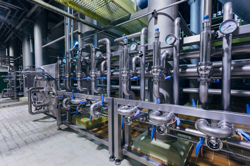 Modern brewery interior. Industrial stainless steel pipes connected with vats and control valves 