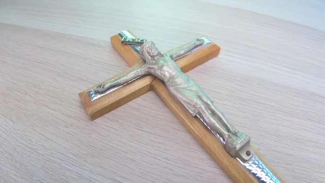 Camera turning around a crucifix on a table. Closeup.