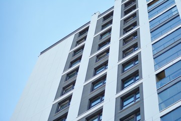Obraz premium Multistory new modern apartment building. Stylish living block of flats. Modern, new executive apartments and with deep blue summer sky