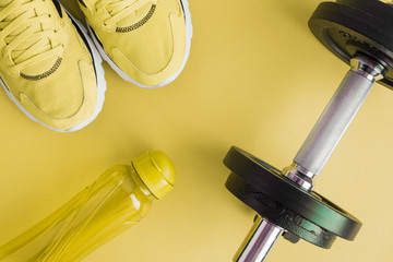 Top view of sport equipment healthy lifestyle concept isolated on yellow.