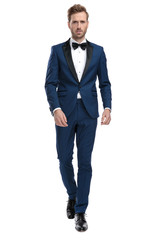 serious man in blue tuxedo walking