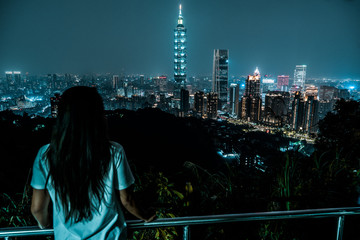 Fototapeta na wymiar A woman overlooks the skyline of Taipei at night. Taiwan. 