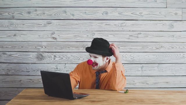 Office worker clown, clown concept at work. Businessman at the computer, work on a laptop.