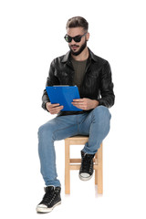 man sitting on chair and reading from blue folder