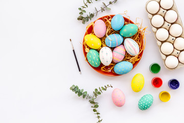 Colorful Easter eggs and paint for celebration on white background top view mock up